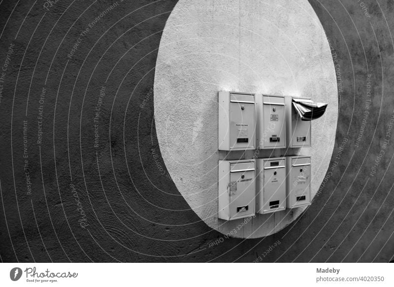 Briefkästen in einem aufgemalten hellen Kreis auf dunkler Fassade in Offenbach am Main in Hessen, fotografiert in klassischem Schwarzweiß Briefkasten Post