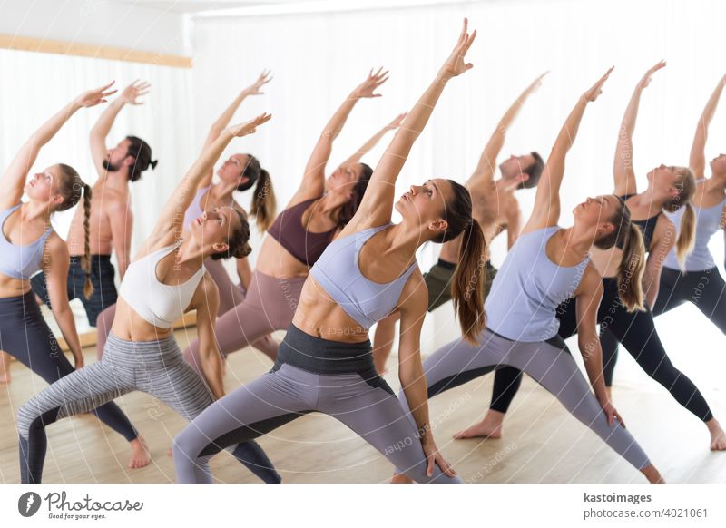 Gruppe junger, authentischer, sportlicher, attraktiver Menschen im Yogastudio, die eine Yogastunde mit einem Lehrer praktizieren. Gesunder aktiver Lebensstil, Training im Fitnessstudio