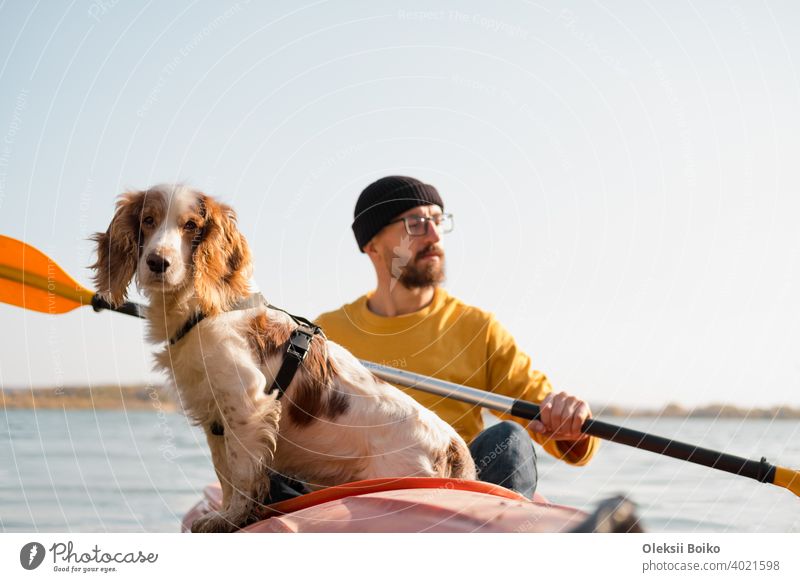 Mann mit einem Hund in einem Kanu auf dem See. Junge männliche Person mit Spaniel in einem Kajak Ruderboot, aktive Freizeit mit Haustieren, Geselligkeit, Abenteuer Hunde
