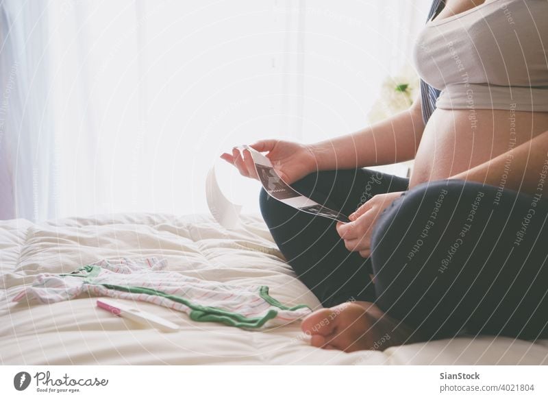 Schwangere Frau mit Blick auf Ultraschall-Scan des Babys schwanger Bett Schwangerschaft Stoff Prüfung Morgen jung Mädchen Sonntag entspannend