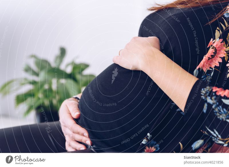 Nahaufnahme einer jungen schwangeren Frau, die ihren Bauch berührt Schwangerschaft schön Glück Leben heimwärts Mutterschaft Pflege Baby Konzept Pflanzen