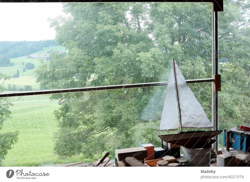 Segelschiff für Kimder mit weißen Segeln auf einer Werkbank in einem alten Bauernhaus mit Blick auf Wiesen und Felder in Rudersau bei Rottenbuch im Kreis Weilheim-Schongau in Oberbayern