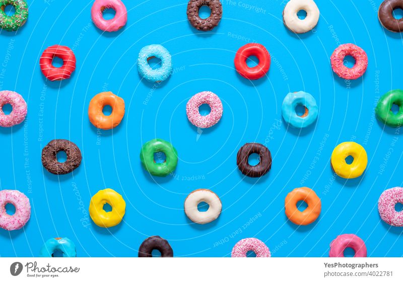 Mehrfarbige Donuts Draufsicht isoliert auf blauem Hintergrund. Glasierte Krapfen Muster. obere Ansicht ausgerichtet sortiert gebacken Bäckerei Schokolade