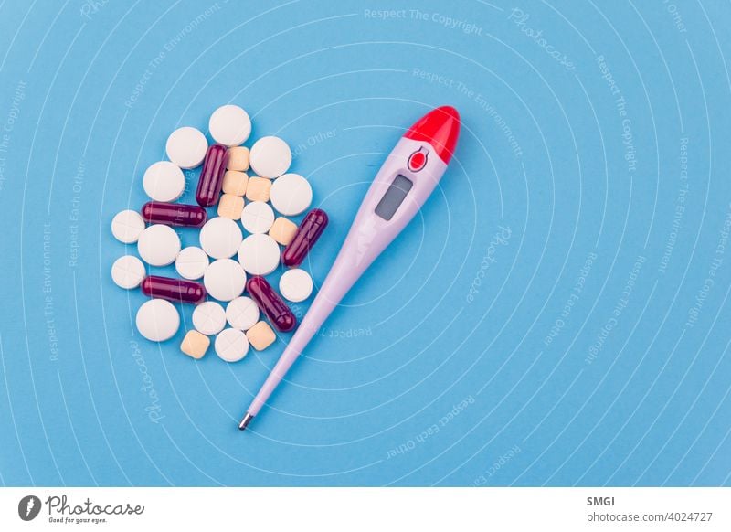 Overhead-Aufnahme von mehreren Pillen und einem Thermometer. Konzept von Medikamenten zur Behandlung von Krankheiten, insbesondere gegen Covid-19 Tablette