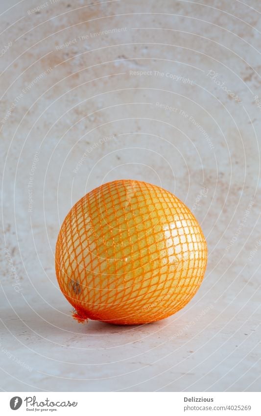Pomelo, einzeln eingewickelt in Netz und Plastikfolie auf neutralem Hintergrund, vertikal mit Copy Space asiatisch asiatische Frucht Zitrusfrüchte Citrus maxima