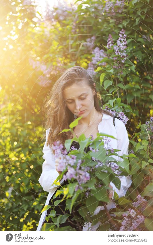 unwirklich schöne junge Frau zu Fuß in einem grünen blühte im Frühjahr in einem Lavendelgarten mit einem Blumenstrauß von Flieder in den Händen. Closeup Mode romantisches Porträt. riechen die Blumen