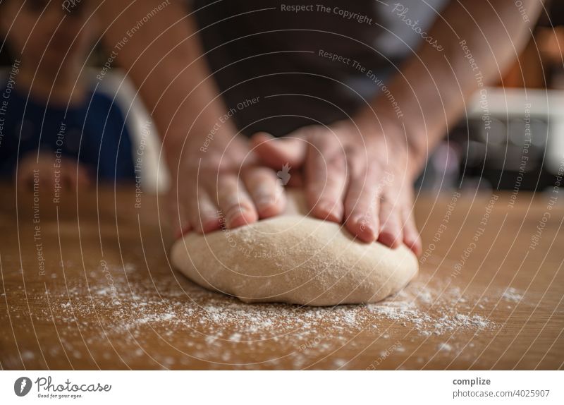Ein Teig wird auf einem Küchentisch geknetet Teigwaren Pizzateig kneten Mehl einstauben selbstgemacht backen Bäckerei Backwaren Brot Brotteig Hände Faust Kind