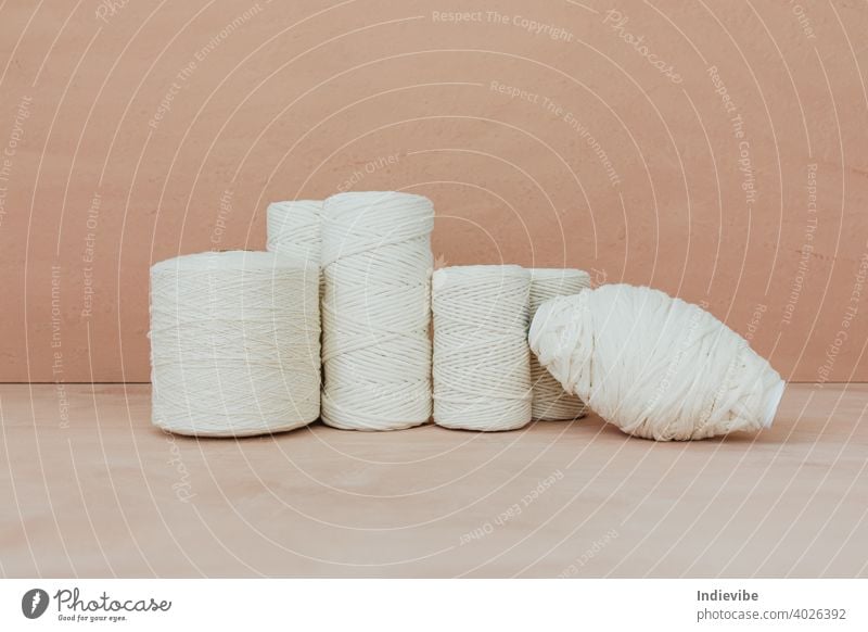Satz von weißen Strickgarn Spule auf beige Hintergrund. Verschiedene Größe Baumwollfäden. stricken Baumwolle Garn Spulen Faser Nähen vereinzelt Schnur Handwerk