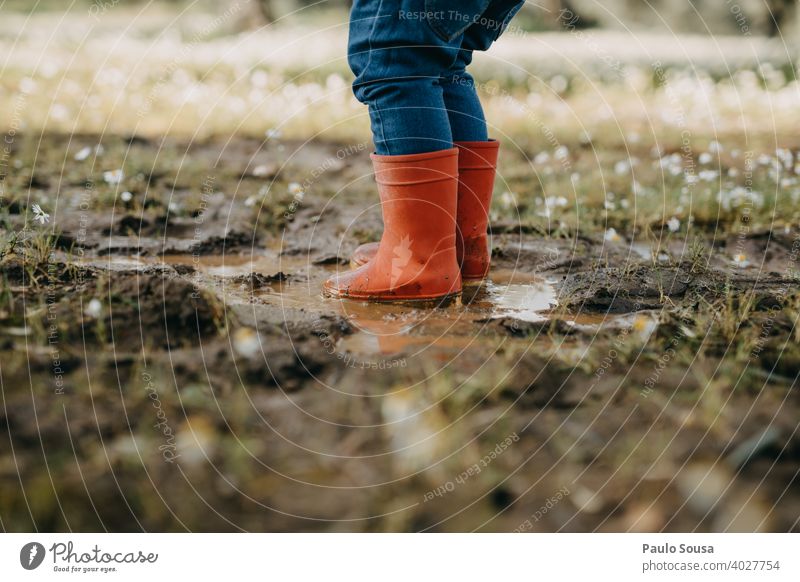 Kind mit roten Gummistiefeln spielt auf einer Pfütze Kindheit Wetter Mensch Wasser Spielen Stiefel Freude nass Regen authentisch Herbst Frühling Winter