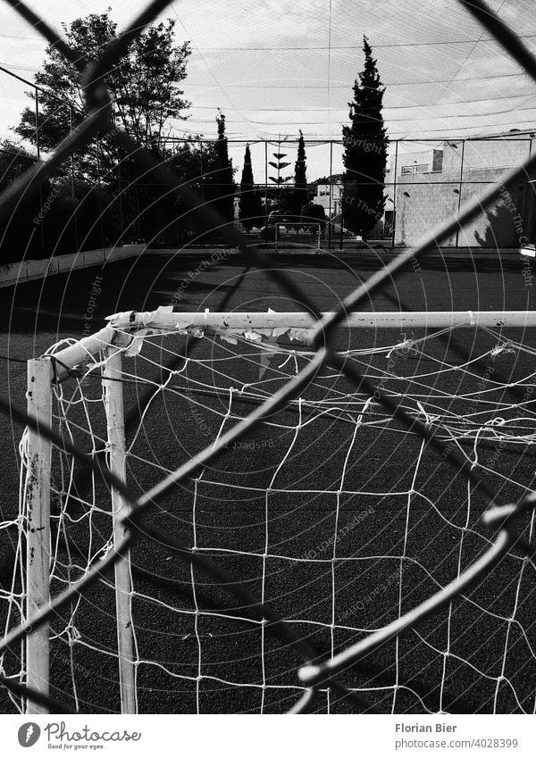 Blick durch einen Zaun auf einen Sportplatz im freien mit gegenüberstehenden Fußballtoren Zuschauer Einblick Hartplatz Belag Spielfeldbegrenzung Trainingsplatz