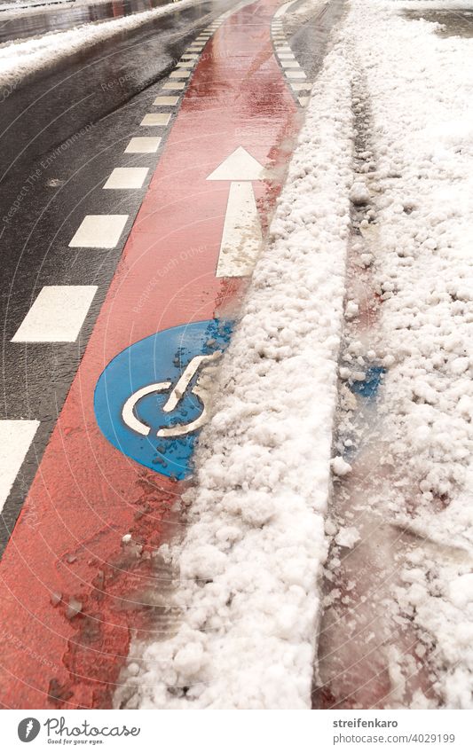 Freie Fahrt voraus! - Roter Fahrradweg drängt sich unter dem Schnee hervor Fahrrad fahren Rad fahren Winter Straße rot blau Symbol Verkehr Verkehrsmittel