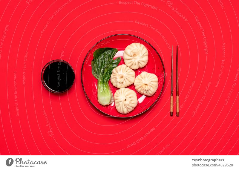 Baozi-Knödel mit Bok Choy auf einem roten Teller, Ansicht von oben. Hausgemachte chinesische gedämpfte Speisen obere Ansicht asiatisch Bao-Knödel Bapao Bok Choi