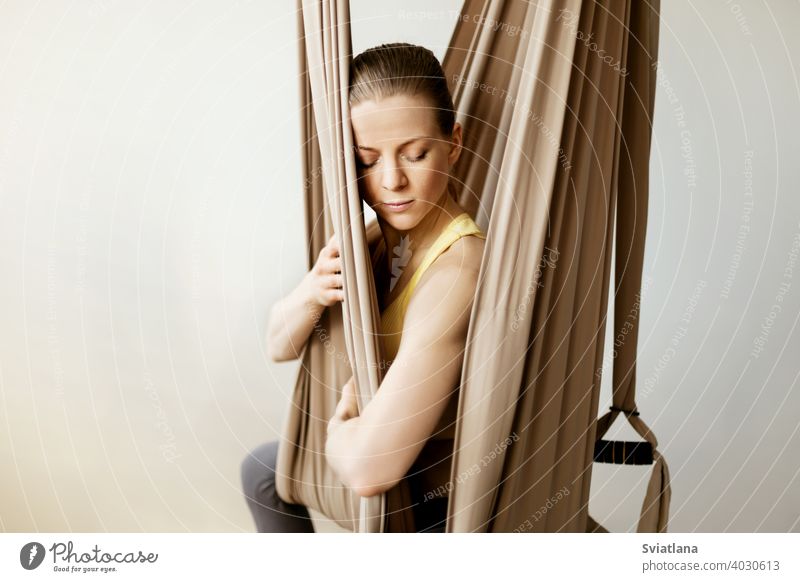 Eine junge Frau meditiert, während sie in einer Hängematte in einer Yogastunde sitzt. Aero Yoga, Sport, gesunder Lebensstil Fitness sich[Akk] entspannen Mädchen