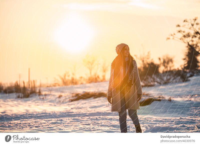 Frau zu Fuß auf verschneiten Feld bei Sonnenuntergang Winter Landschaft Schnee Glück Spaziergang Natur Saison genießen froh frisch kalt heiter schlendern