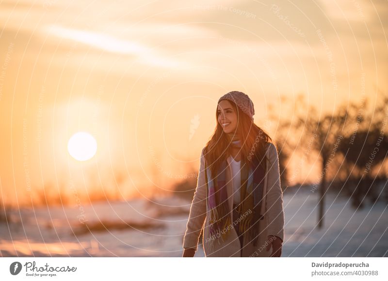 Frau zu Fuß auf verschneiten Feld bei Sonnenuntergang Winter Landschaft Schnee Glück Spaziergang Natur Saison genießen froh frisch kalt heiter schlendern
