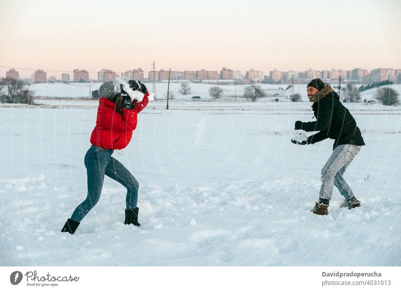 Fröhliches Paar spielt Schneebälle im Winter Feld Schneeball Spaß haben spielen heiter genießen Zusammensein Landschaft Liebe romantisch Partnerschaft Zuneigung