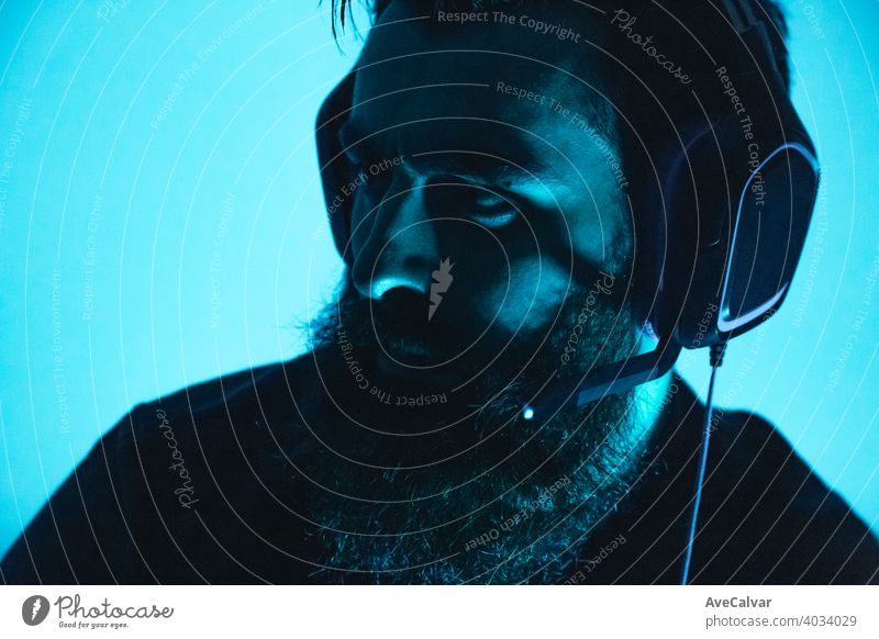 Ein junger Mann mit Bart hält ein Gaming-Headset auf ernstes Gesicht Spiel männlich Person Computer Entertainment Typ online Spieler Internet spielen Spaß
