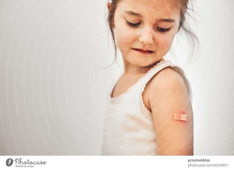 Kleines Mädchen, das nach der Impfung Schmerzen hat, hat einige Nebenwirkungen. Rötung, Schwellung, Gliederschmerzen und Kopfschmerzen als Reaktion nach der Impfung