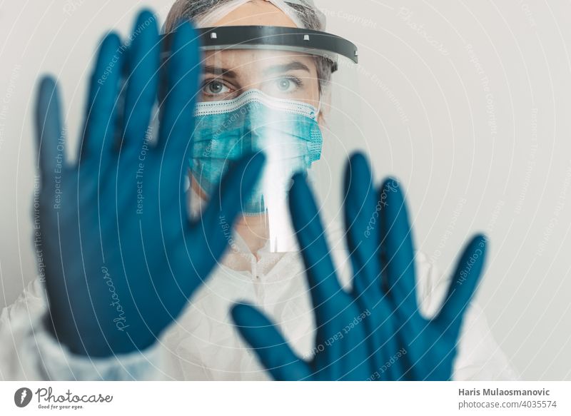 Mitarbeiter im Gesundheitswesen mit Schild und Maske zeigt Stopp-Geste Kur Krankheit Arzt England Seuche Experiment Frankreich Deutschland Handschuhe