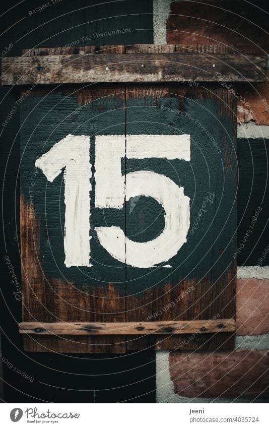 Hausnummer fünfzehn geschrieben als Zahl 15 auf einem rustikalen Holzbrett mit weißer Farbe auf dunklem Hintergrund Ziffern & Zahlen ziffer Ziffern und Zahlen