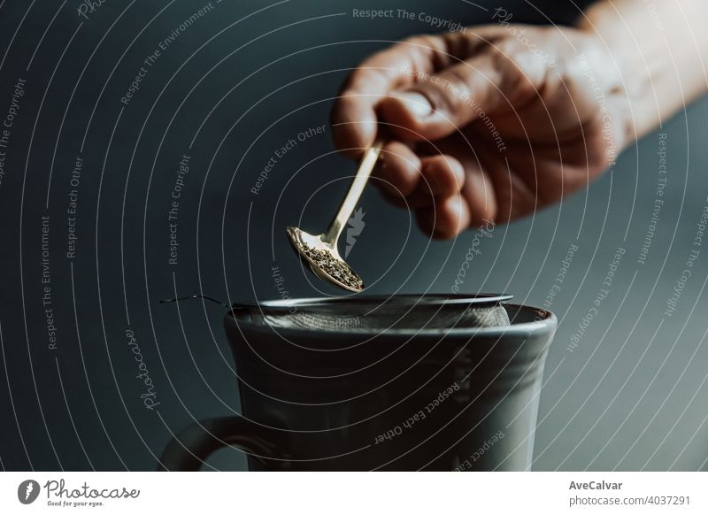 Eine alte Hand, die einen Tee über einen dunklen Hintergrund mit Kopierraum und dunklen Tönen vorbereitet trinken Tasse Wasser heiß Frau Küche Person eingießen