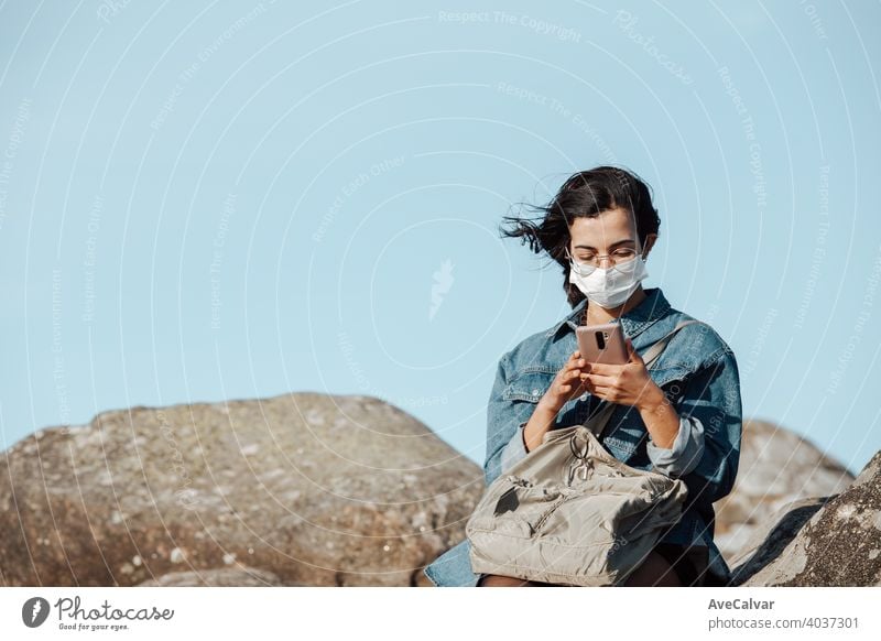 Eine junge Frau, die eine Maske trägt, überprüft sein Telefon, während der Wind mit Kopie Raum weht Mobile Menschen Natur Person Lächeln Glück schön Funktelefon