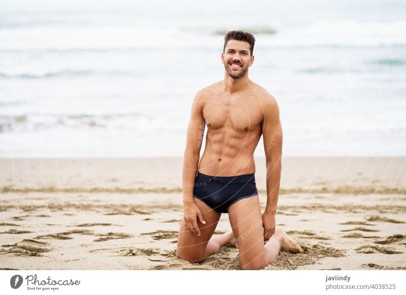Hübscher Mann auf den Knien auf dem Sand des Strandes sexy männlich muskulös gutaussehend Gesundheit Wasser Menschen passen MEER Model Bauchmuskeln Urlaub