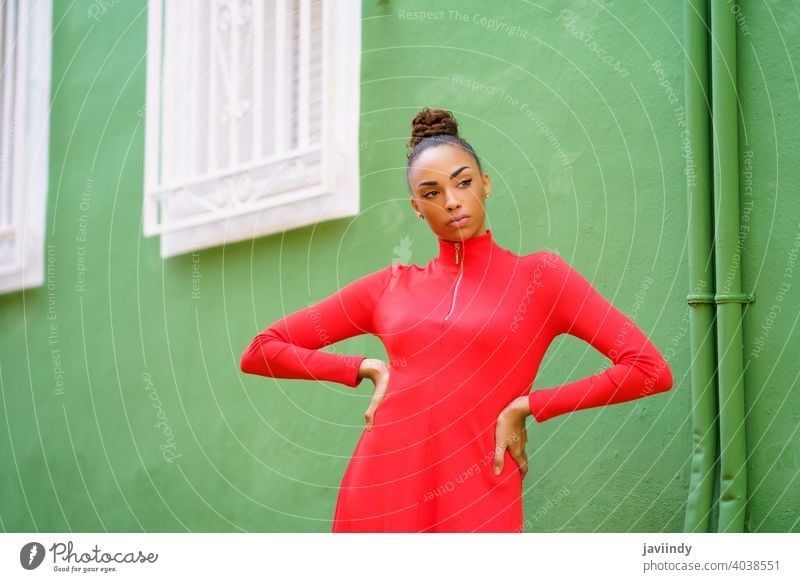 Junge gemischte Frau in rotem Kleid vor einer grünen Wand schwarz Schleife ernst Frisur Behaarung Model Schönheit hübsch Porträt Mädchen jung Person Dame Sommer