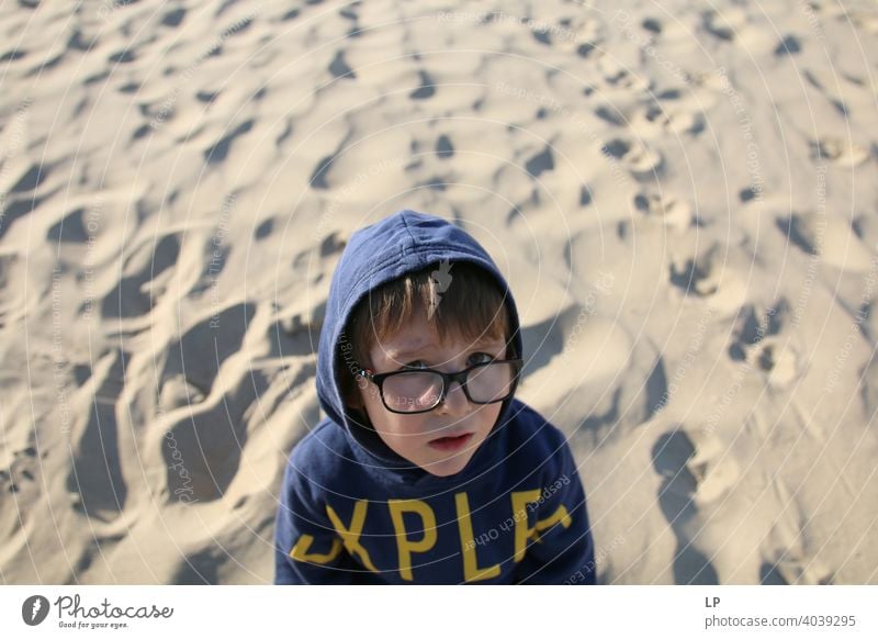 schönes Kind mit Brille und Kapuzenpulli schaut sehr ernst in die Kamera verwirrt ratlos skeptisch Skepsis Zweifel hestitate Unsicherheit Verwirrung Kindheit