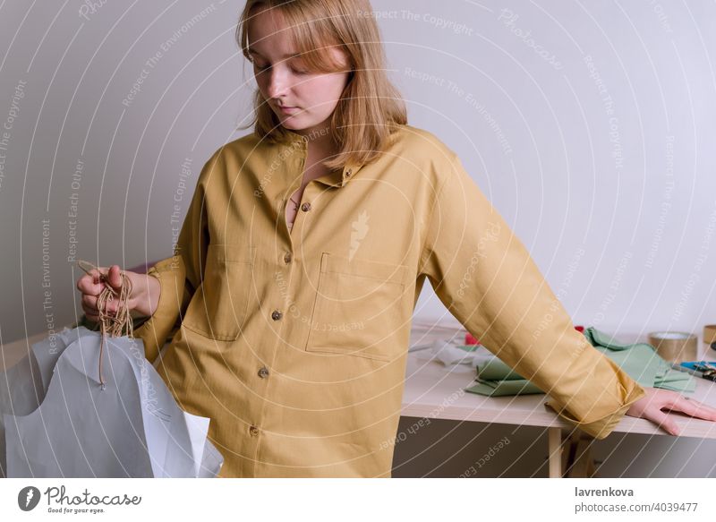 Frau in gelbem Hemd hält Papierkleidmuster in ihrer Werkstatt Schneider Handwerk Damenschneiderin Mode Muster Kleid Kleidungsmuster Bekleidung Beruf