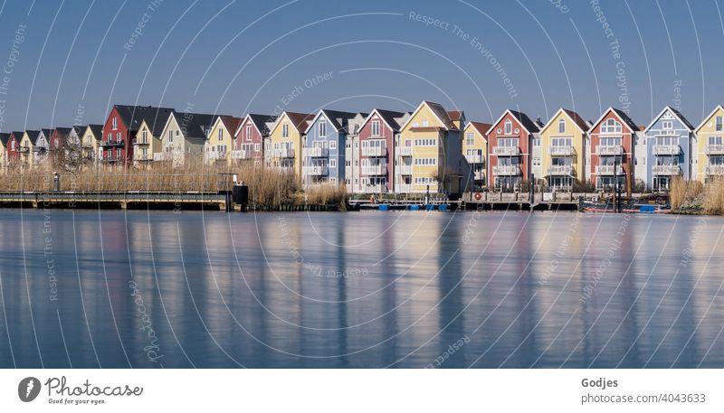 Langzeitbelichtung von bunten Holzhäusern (Schwedenhäuser) mit Bootsanlegern an einem Fluss Gedeckte Farben blau Seeufer Weitwinkel Textfreiraum unten kalt