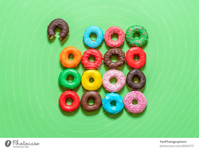 Schokoladen-Donuts mit mehrfarbigem Zuckerguss, Draufsicht auf grünem Hintergrund. obere Ansicht ausgerichtet sortiert gebacken gebissen blau Kuchen farbenfroh