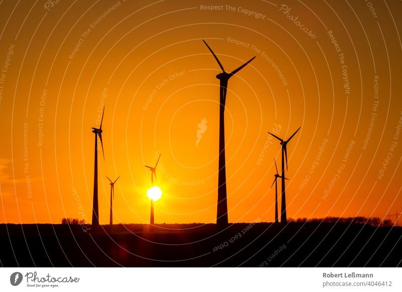 viele Windräder bei Sonnenuntergang stehen auf einem Feld und produzieren Strom windräder ökostrom umweltfreundlich klimaschutz abendrot sonnenuntergang