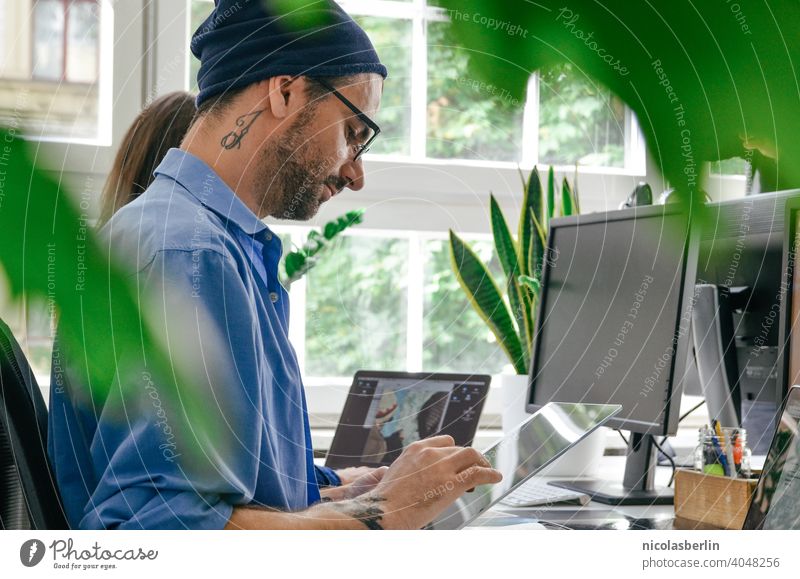 Junger Mann mit Tattoo arbeitet am Laptop im Büro Freiberufliche Tätigkeit Computer Verwendung des Laptops Hipster Technik & Technologie Drahtlos Jahrtausende