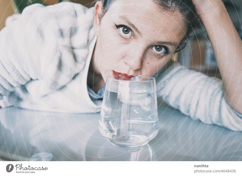 Porträt einer jungen Frau, verdeckt durch ein Glas mit einem transparenten Getränk Depression blau traurig mental Gesundheit Psychologie Traurigkeit depressiv