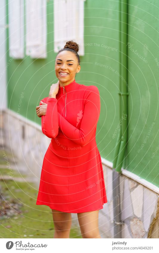 Glückliche schwarze Frau im roten Kleid vor einer grünen Wand Lächeln Schleife Frisur Behaarung Model Schönheit hübsch Porträt Mädchen Fröhlichkeit jung Person