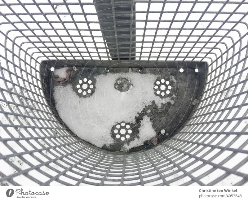 Blick von oben in einen verschneiten leeren Abfallkorb aus Metallgitter mit gestanztem Blümchenmuster am Boden Mülleimer Schnee kalt Muster Umwelt Winter