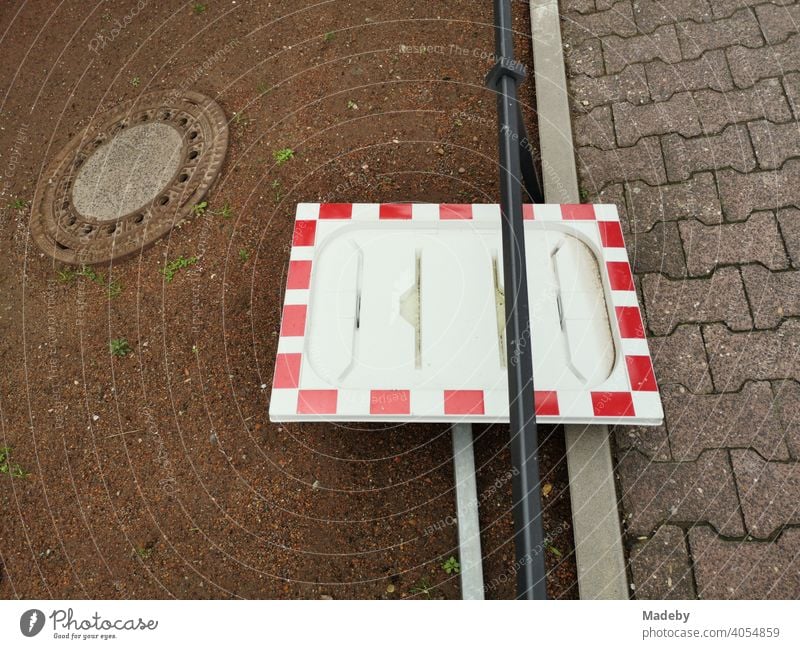 Rahmen eines Verkehrsspiegel in Rotweiß ohne Spiegel als Stillleben mit Gullydeckel am Straßenrand im Stadtteil Bockenheim in Frankfurt am Main in Hessen