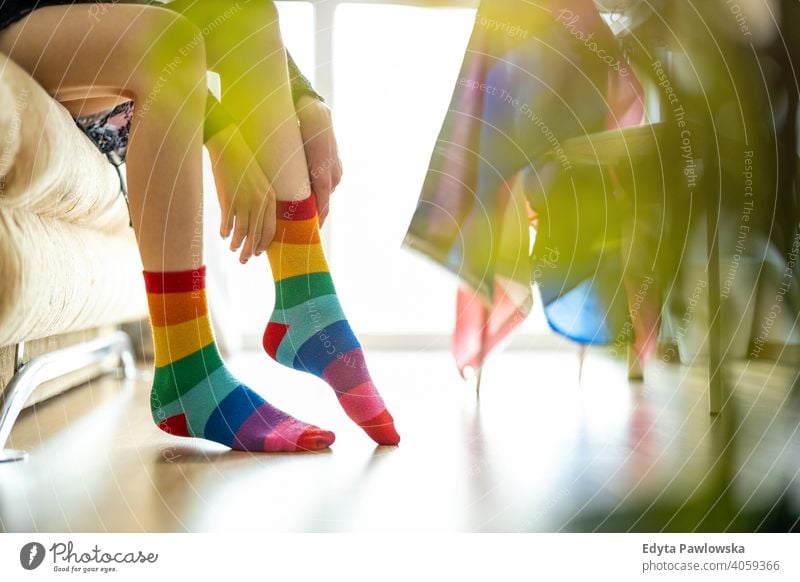 Nahaufnahme einer Person, die Regenbogensocken anzieht lgbtq Regenbogenflagge Socken echte Menschen Stolz Beine nicht-binär geschlechtsfluid Gender-Fluidität