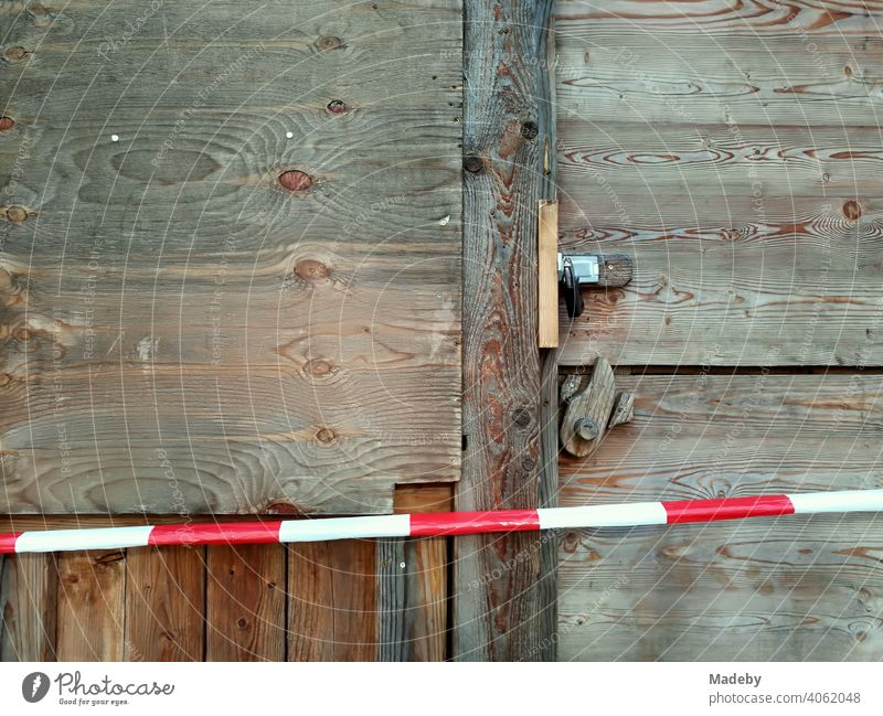 Rotweißes Absperrband vor einer Holzhütte mit Holztür aus rustikalem Holz mit Vorhängeschloss vor Beginn des Weihnachtsmarktes in der Hansestadt Lemgo bei Detmold in Ostwestfalen-Lippe