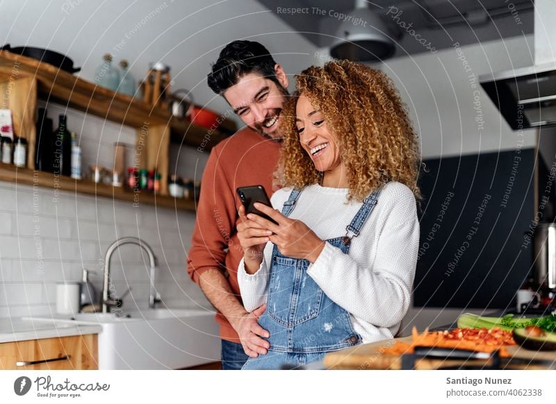 Pärchen schaut in der Küche auf ein Smartphone. Lebensmitte Paar Liebe Essen zubereiten heimwärts gemütlich Kaukasier Partnerschaft vorbereitend Frau Glück