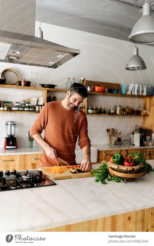 Mann bereitet Essen in der Küche vor. Lebensmitte Paar Liebe Essen zubereiten heimwärts gemütlich Kaukasier Partnerschaft vorbereitend Glück Person Herd allein