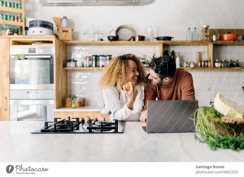 Ehepaar schaut in der Küche auf einen Laptop. Lebensmitte Paar Liebe Essen zubereiten heimwärts gemütlich Kaukasier Partnerschaft vorbereitend Frau Glück Person