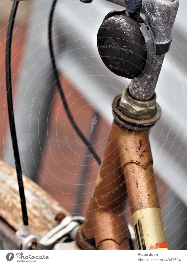 Detailaufnahme einer Fahrradklingel überzogen mit schwarzer Patina an einer angelaufenen Lenkerstange an einem verrosteten Fahrrad Klingel rostig alt retro