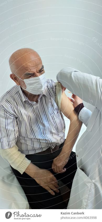 Alter türkischer Mann, der von einer Krankenschwester in einem Krankenhaus den Impfstoff Covid 19 in den Arm gespritzt bekommt Bund 19 Schuss Einspritzung