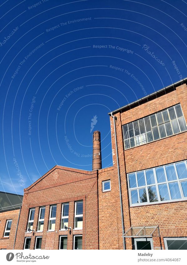 Alte Fabrikgebäude und hoher Fabrikschornstein mit schöner Fassade vor blauem Himmel bei Sonnenschein in der Hansestadt Lemgo bei Detmold in Ostwestfalen-Lippe