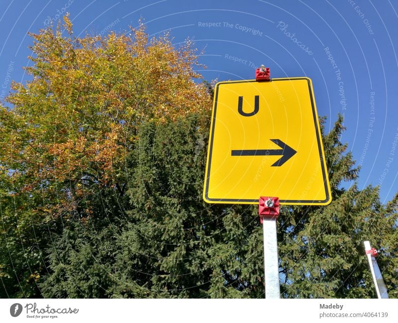 Gelbes Verkehrszeichen mit dem Hinweis auf eine Umleitung vor großen alten Bäumen und blauem Himmel im Herbst bei Sonnenschein in der Hansestadt Lemgo bei Detmold in Ostwestfalen-Lippe