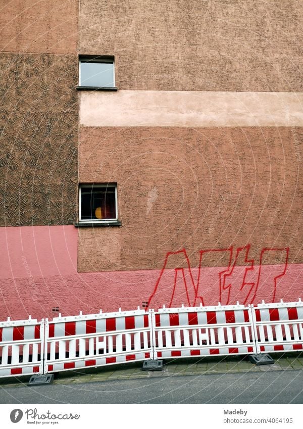Fassade mit zwei Fenstern und Farbestaltung in Rosa und Brauntönen mit Graffiti und Bauzaun in Offenbach am Main in Hessen Anstrich Putz Farbgebung
