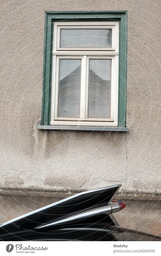 Große schwarze Heckflisse eines amerikanischen Straßenkreuzer der Fünfzigerjahre vor dem Fenster eine alten Haus bei den Golden Oldies in Wettenberg Krofdorf-Gleiberg bei Gießen in Hessen
