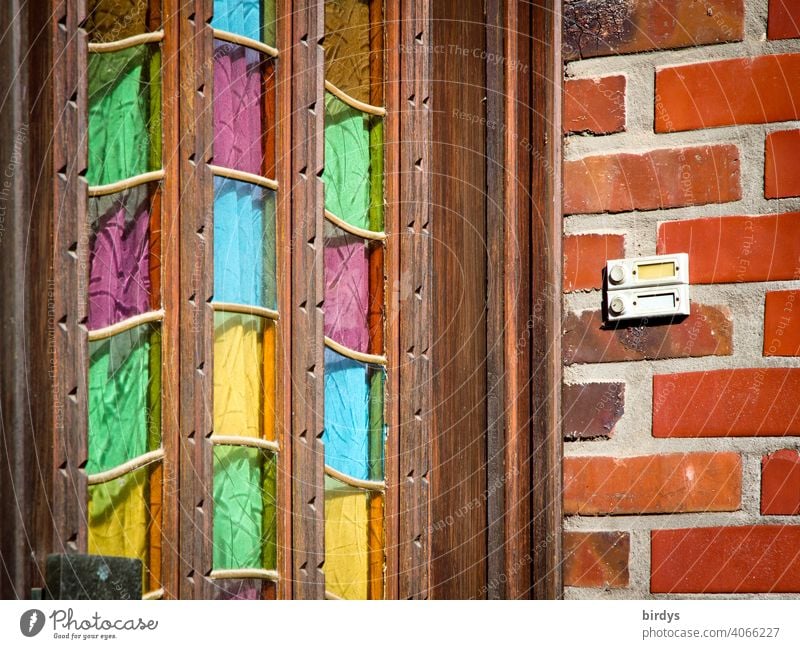 Alte hölzerne Hauseingangstür mit bunten Glasscheiben, Backsteinwand mit Klingel.Eingang Tür Haustür Holztür mehrfarbig freundlich Eingangstür alt lila gelb